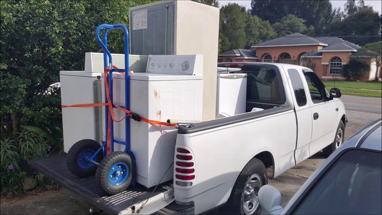 Old washing machines and dryers loaded onto a pickup truck for disposal, representing appliance removal services Kent WA.